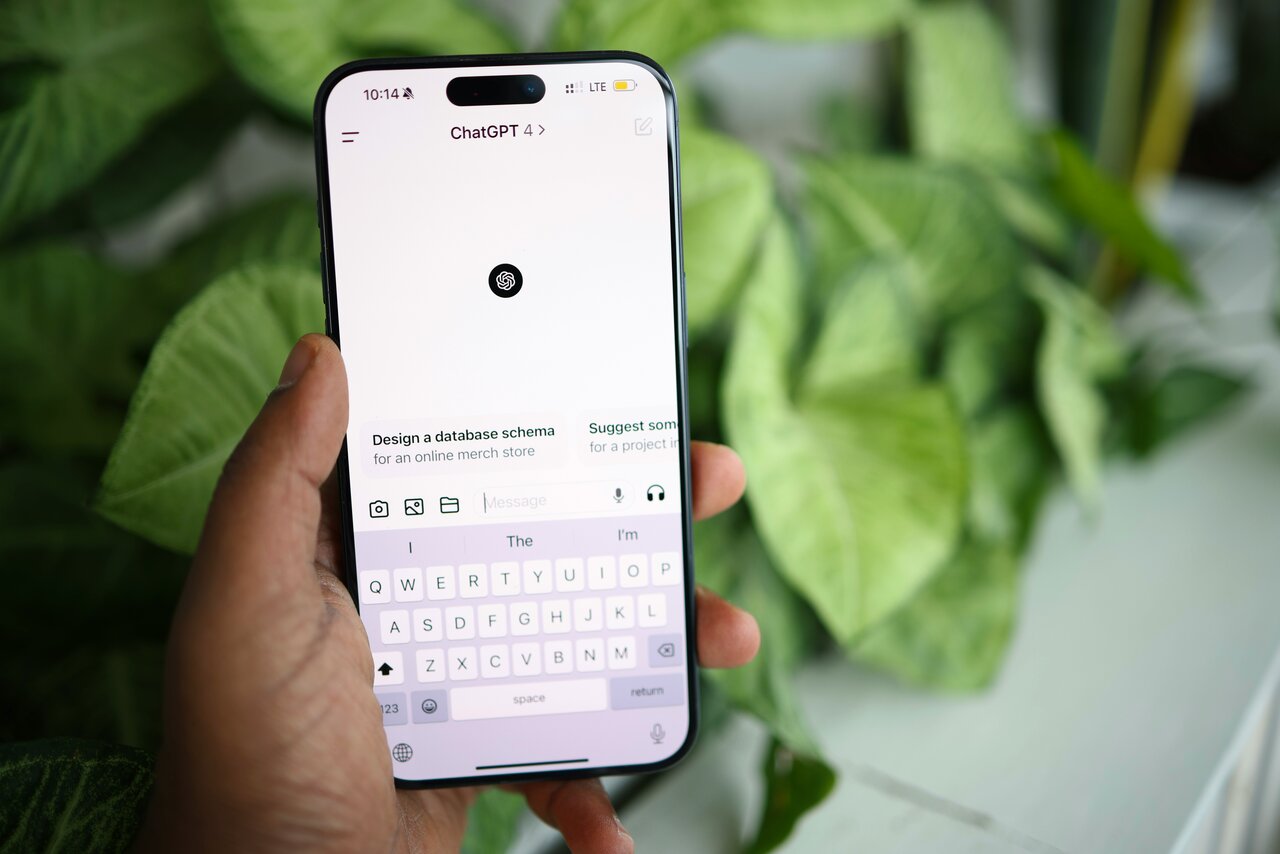 A hand holding a smartphone showing a ChatGPT conversation, representing how New Zealanders now research local services through AI-powered answer engines