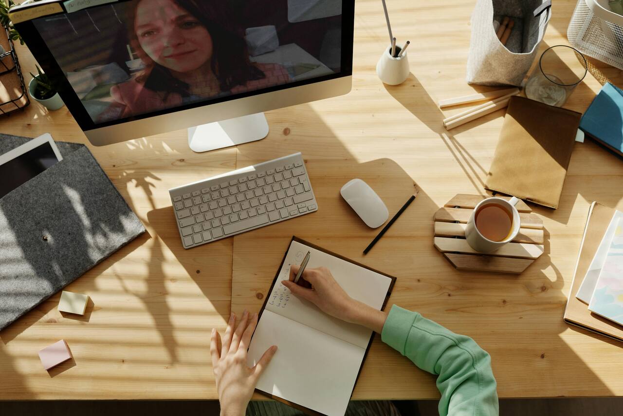 Sunlit warm wood desk with notebook, keyboard, and coffee