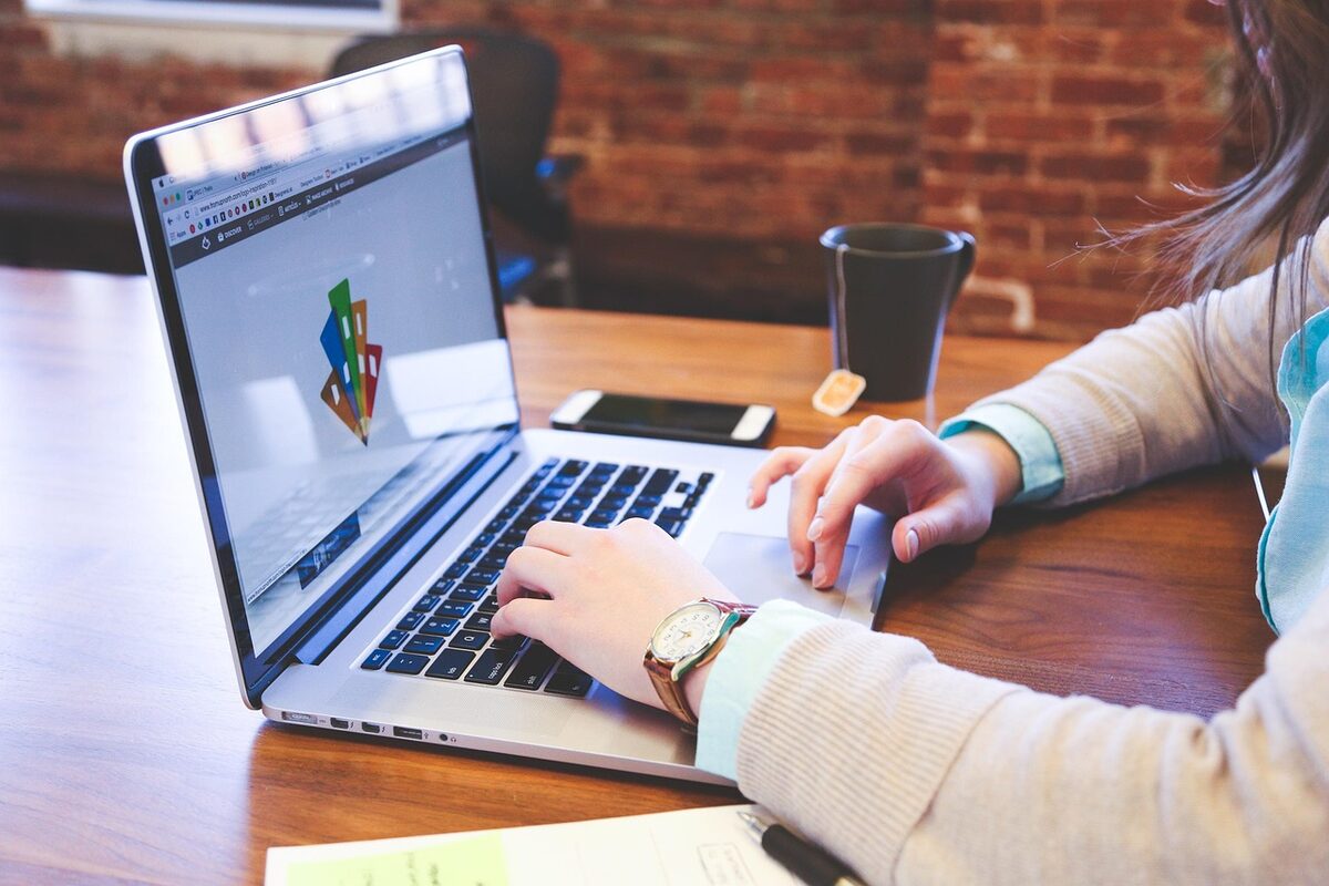 Hand-drawn illustration of an Auckland small business owner comparing website design pricing options on a laptop, with the Auckland skyline in the background