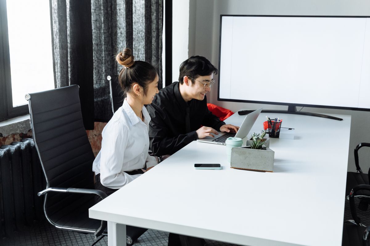 两位商务人士在办公室一起查看笔记本电脑上的数据