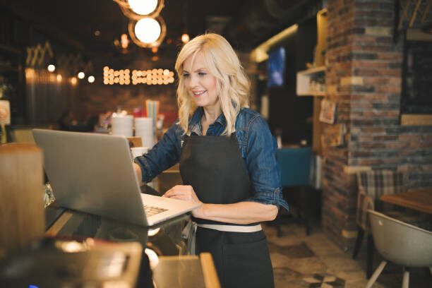 Business owner planning a new website on a laptop in their café
